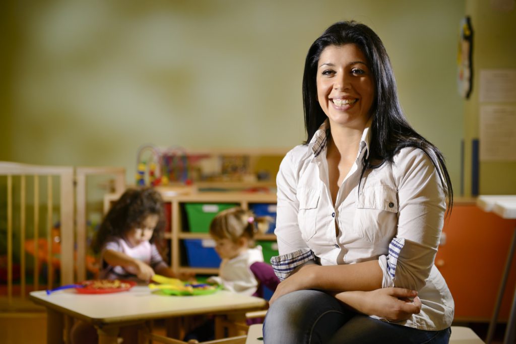happy teacher with children eating in kindergarten