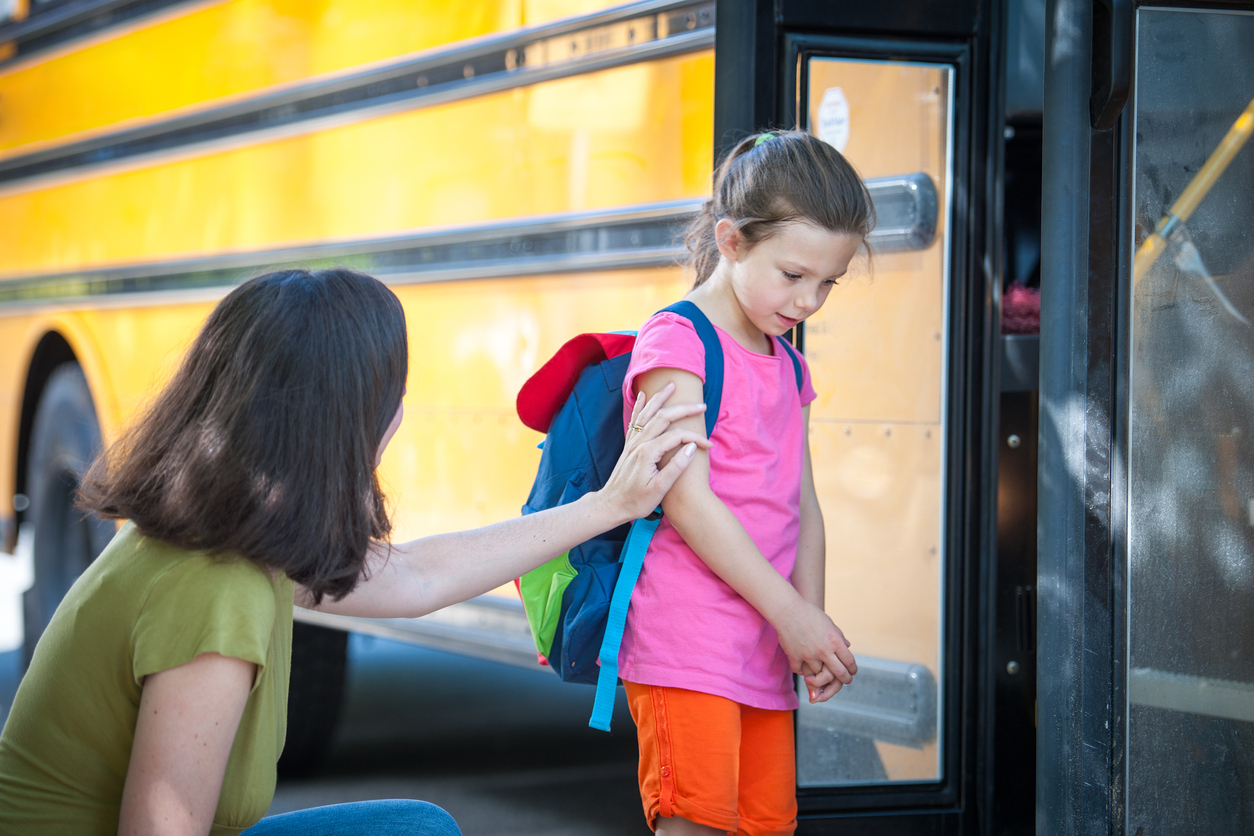Child Care Provider Encouraging a Child to Board School Bus